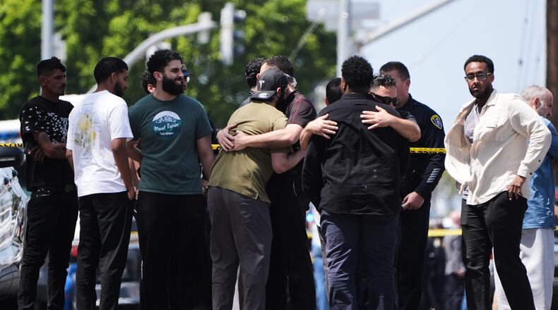 People embrace near the scene of a shooting outside the Islamic Center of San Diego Monday, May 18, 2026, in San Diego. (AP Photo/Gregory Bull)