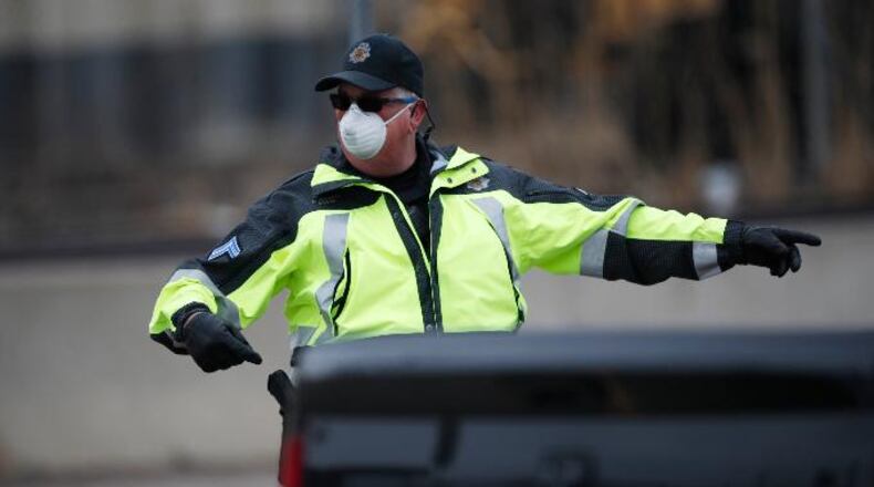 A Denver Police Department officer wears a surgical mask while directing traffic at a coronavirus drive-thru testing site outside the Denver Coliseum Saturday, March 14, 2020, in Denver. (AP Photo/David Zalubowski)