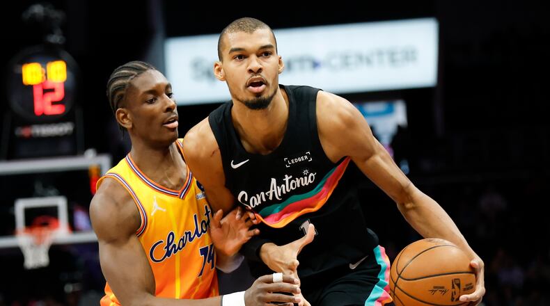 San Antonio Spurs forward Victor Wembanyama, right, moves the ball against Charlotte Hornets forward Moussa Diabate during the first half of an NBA basketball game in Charlotte, N.C., Saturday, Jan. 31, 2026. (AP Photo/Nell Redmond)