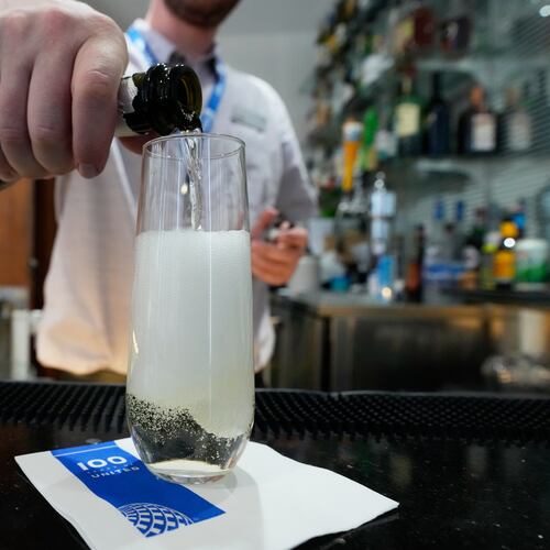 A bartender pours a glass of sparkling wine at the United Club lounge, Monday, June 29, 2026, in Minneapolis, Minn. (AP Photo/Chris Carlson)