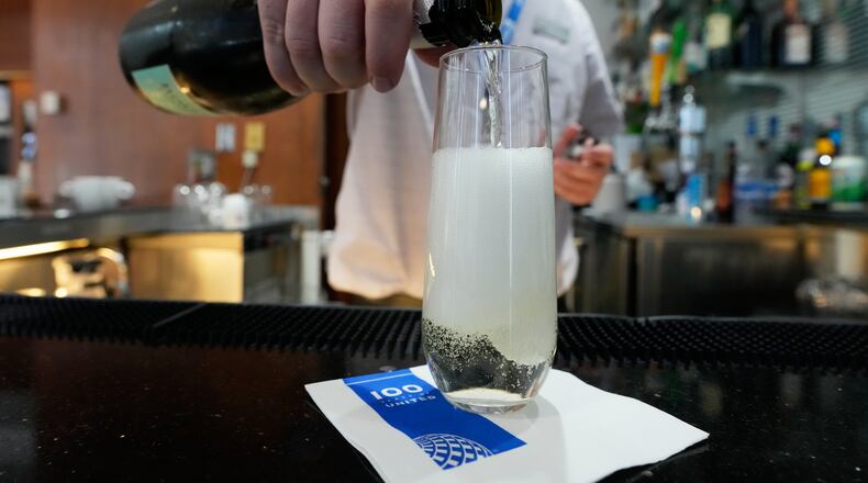 A bartender pours a glass of sparkling wine at the United Club lounge, Monday, June 29, 2026, in Minneapolis, Minn. (AP Photo/Chris Carlson)