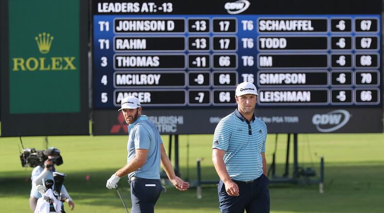 The leaders tied at 13 under par Dustin Johnson (left) and Jon Rahm (right) check out their shots on the 18th green during the first round of the Tour Championship at East Lake Golf Club on Friday, Sept. 4, 2020 in Atlanta.  Curtis Compton / Curtis.Compton@ajc.com