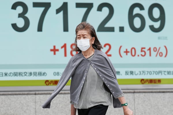 A person walks in front of an electronic stock board showing Japan's Nikkei index at a securities firm Friday, May 23, 2025, in Tokyo. (AP Photo/Eugene Hoshiko)