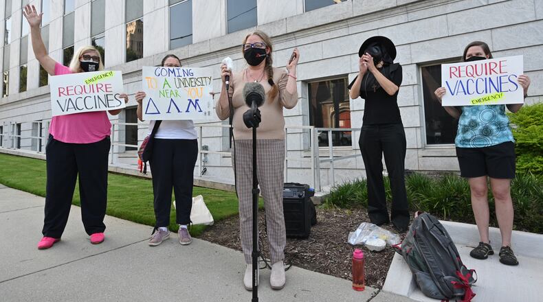 Therese Poole (center), senior lecturer at Georgia State University, reads her statement during a rally urging the University System of Georgia to institute a policy requiring everyone wear masks or be vaccinated to be on campus, outside the building in downtown Atlanta where the Board of Regents meets on Tuesday, Aug. 10, 2021 (Hyosub Shin / Hyosub.Shin@ajc.com)