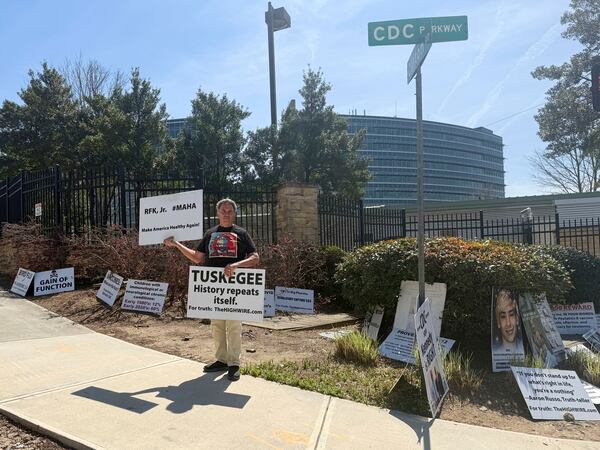 Mike Arnold, a supporter of Health Secretary Robert F. Kennedy Jr., holds signs as he protests against the CDC outside the CDC campus in Atlanta, Thursday, March 27, 2025. (AP Photo/Kenya Hunter)