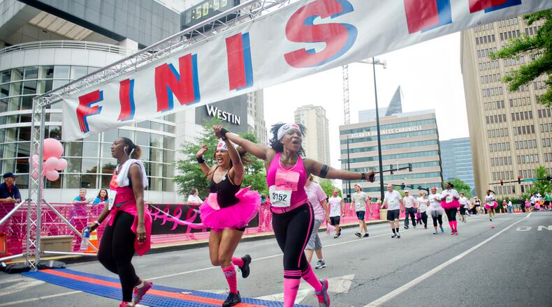 Chi Michaels (right) and Leesa Mendes hold hands as they cross the finish line for the Susan G. Komen Race for the Cure at Lenox Square Mall on Saturday, May 10, 2014.