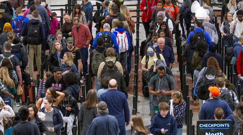 Travelers weave through a long line to get to the security checkpoint at Hartsfield-Jackson International Airport. Economists say that fear can convince people to travel less, avoid crowds and spend less money. STEVE SCHAEFER / SPECIAL TO THE AJC