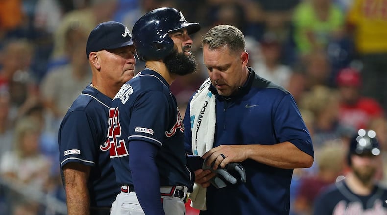 Nick Markakis #22 of the Atlanta Braves is looked at by a member of the team's medical staff along with manager Brian Snitker #43 after getting hit in the hand by a pitch during the sixth inning of a game against the Philadelphia Phillies at Citizens Bank Park on July 26, 2019 in Philadelphia, Pennsylvania. The Braves defeated the Phillies 9-2. (Photo by Rich Schultz/Getty Images)
