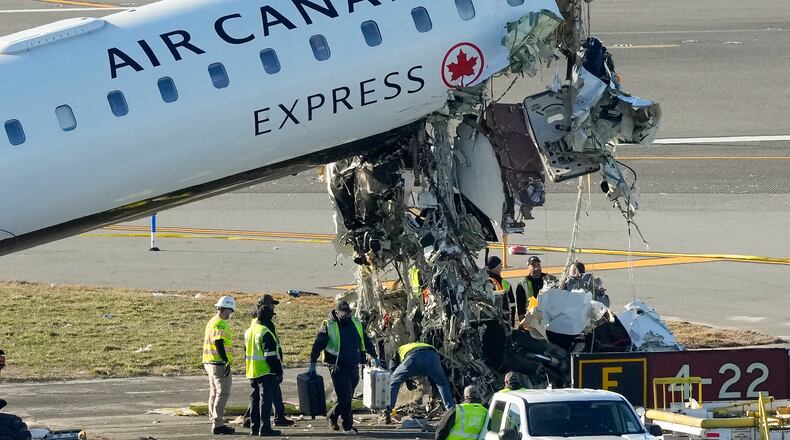 NTSB officials and aircraft maintenance workers pick through debris and remove luggage as they inspect the wreckage of an Air Canada Express jet, Tuesday, March 24, 2026, just off the runway where it had collided with a Port Authority fire truck Sunday night at LaGuardia Airport in New York. (AP Photo/Yuki Iwamura)