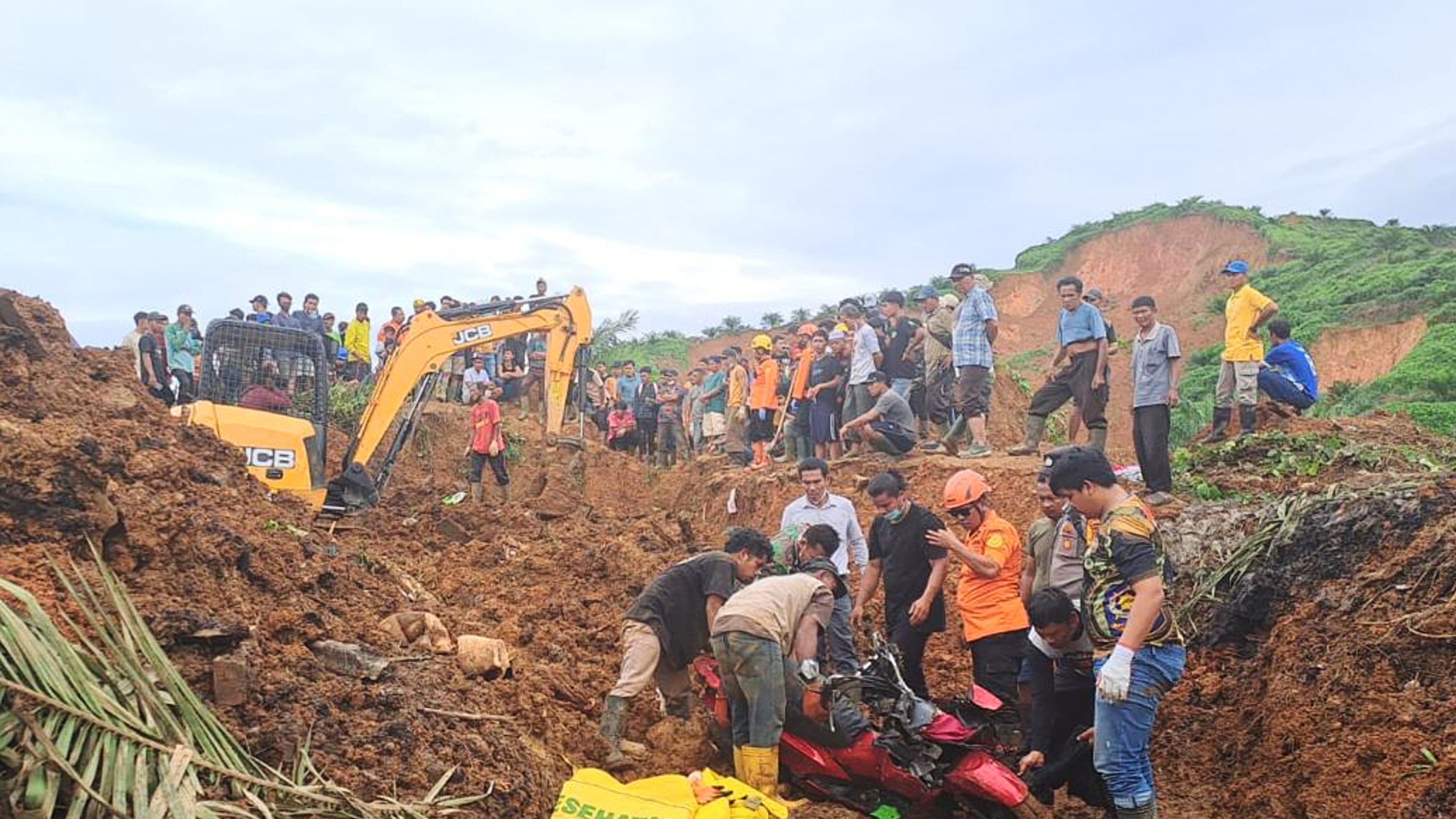 In this photo released on Saturday, Nov. 29, 2025 by the Indonesian National Search and Rescue Agency (BASARNAS), rescuers remove a scooter buried in the mud as they search for victims at a village hit by a landslide in Batu Goading, North Sumatra, Indonesia. (BASARNAS via AP)