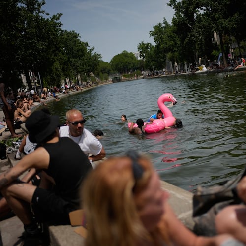 Parisians bath in the Canal Saint-Martin in Paris, as the national weather service, Meteo France, placed 54 departments, about half the country, under a red heat wave alert, Tuesday, June 23, 2026. (AP Photo/Christophe Ena )