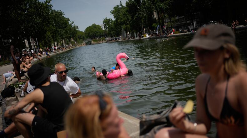 Parisians bath in the Canal Saint-Martin in Paris, as the national weather service, Meteo France, placed 54 departments, about half the country, under a red heat wave alert, Tuesday, June 23, 2026. (AP Photo/Christophe Ena )