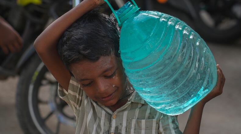 A boy carries a water can which he collect from a public tap in Mumbai, India, Saturday, June 20, 2026. (AP Photo/Rafiq Maqbool)