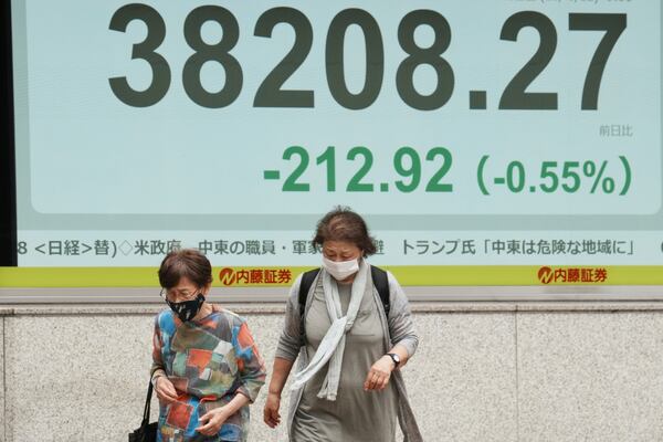 People walk in front of an electronic stock board showing Japan's Nikkei index at a securities firm Thursday, June 12, 2025, in Tokyo. (AP Photo/Eugene Hoshiko)