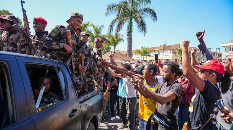 Soldiers are greeted by people gathering for a ceremony in tribute to demonstrators killed during recent anti-government protest in Antananarivo, Madagascar, Sunday, Oct. 12, 2025. (AP Photo/Mamyrael)