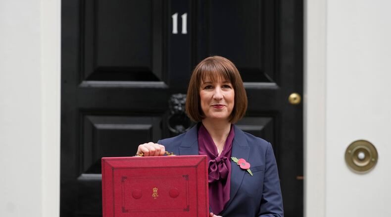 FILE - Britain's Chancellor of the Exchequer, Rachel Reeves, holds up the traditional red ministerial box containing her budget speech, as she poses for the media outside No 11 Downing Street, before departing to the House of Commons to deliver the budget in London, Wednesday, Oct. 30, 2024. (AP Photo/Kirsty Wigglesworth, File)