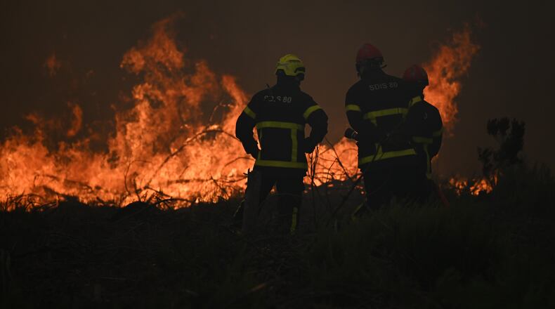 Firefighters spray water in a burning forest near Lacanau, southwestern France, Saturday, July 25, 2026. (AP Photo/Emma Da Silva)