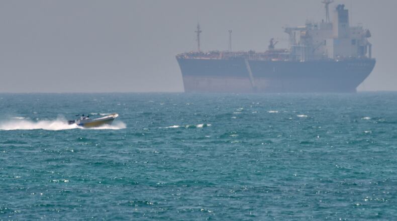 FILE - A boat sails past a tanker anchored on the Strait of Hormuz off the coast Qeshm island, Iran, April 18, 2026. (AP Photo/Asghar Besharati, File)