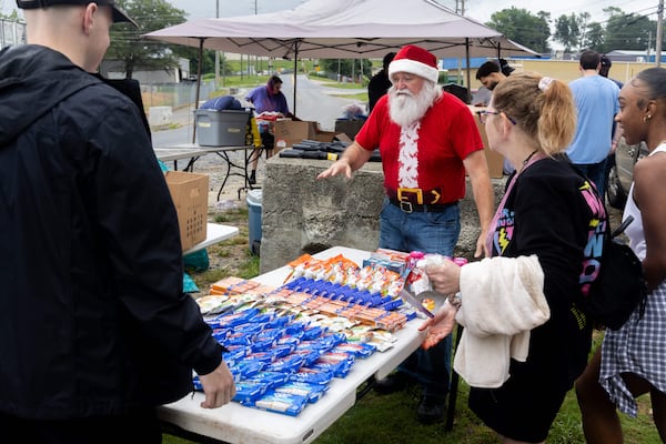 Randy Smith (center, in red) directs Santa for the Homeless volunteers as they set out food tables near a homeless encampment in Gainesville. "Santa Randy" leads the group, comprised of members from 10 different churches, providing much-needed supplies to the estimated 104 people who live at the encampment on the first Saturday of the month. (Phil Skinner for the AJC)