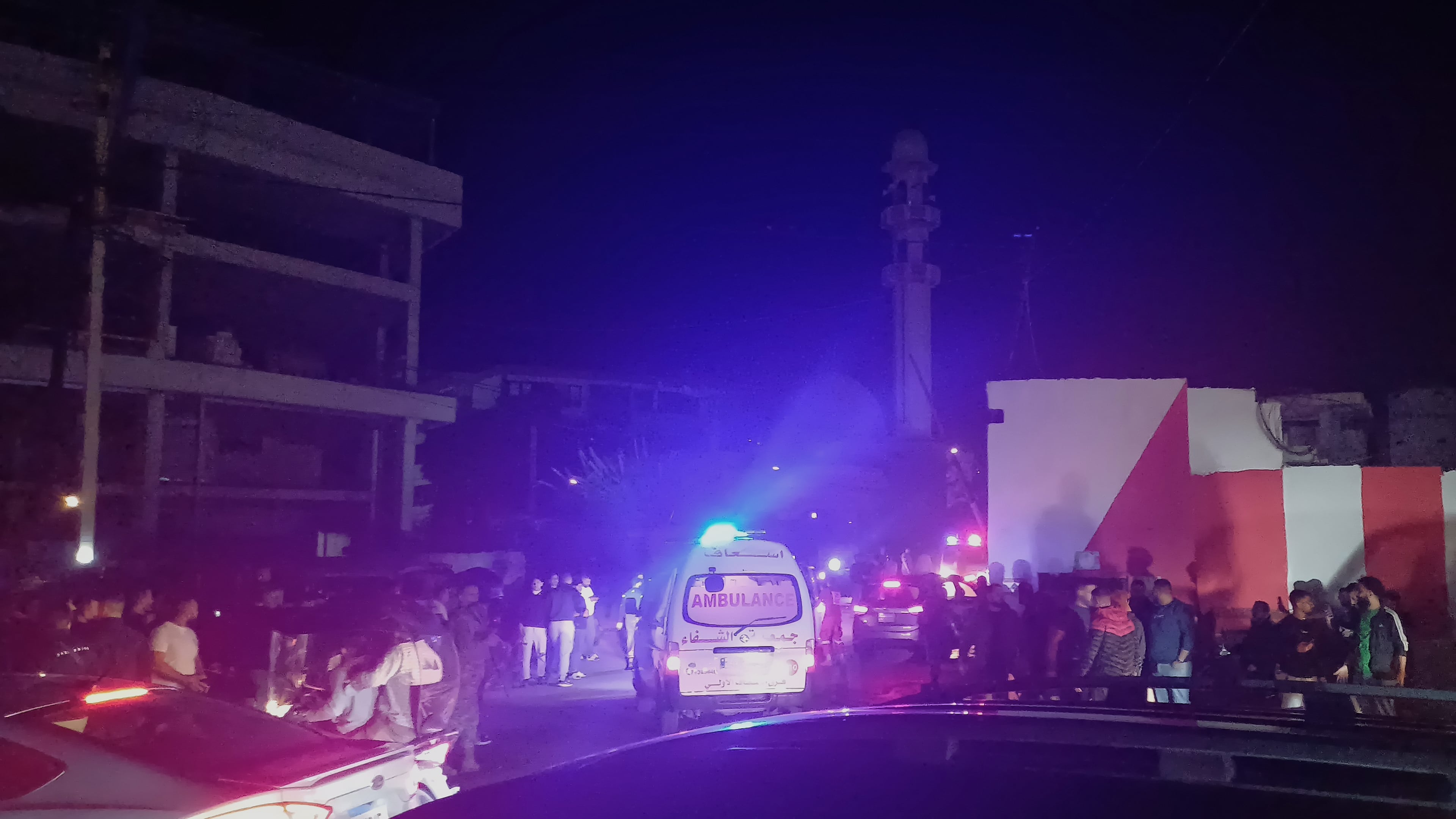 People gathering next of an ambulance as it enters the Ein el-Hilweh refugee camp in the southern port city of Sidon, Lebanon, Tuesday, Nov. 18, 2025. (AP Photo/Mohammed Zaatari)