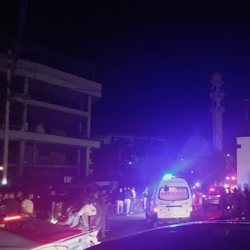 People gathering next of an ambulance as it enters the Ein el-Hilweh refugee camp in the southern port city of Sidon, Lebanon, Tuesday, Nov. 18, 2025. (AP Photo/Mohammed Zaatari)