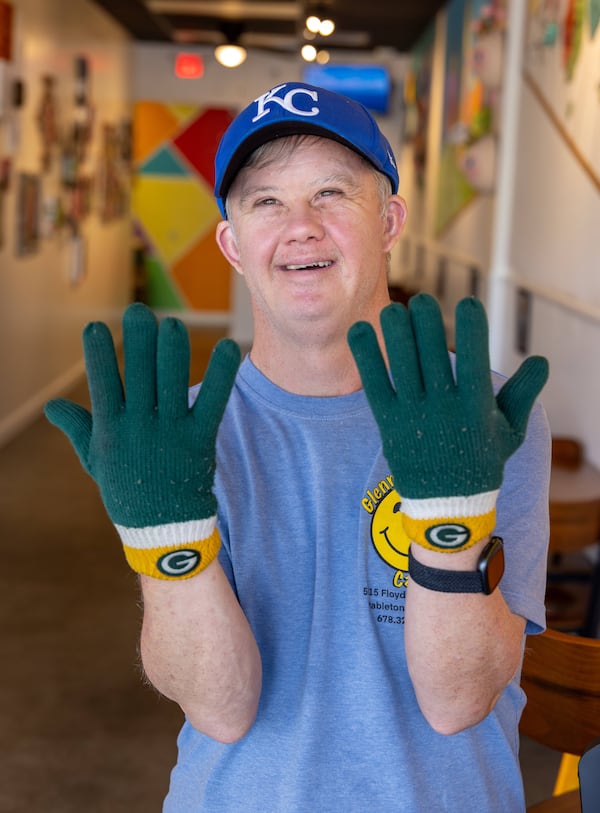 A big sports fan, Glenn Hutchinson wears Green Bay Packers gloves and a Kansas City cap as he works at Glenn's Cafe, which bears his name.  (Phil Skinner for the AJC)
