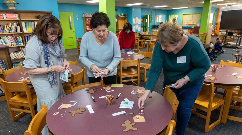 Christ Child Society volunteers Patti Anhut (from left), Casey Long and Nancy Nadolski set up crafts for pre-K and kindergarten students in the Saint Peter Claver Regional Catholic School library. Volunteers with the nonprofit Christ Child Society help needy children in several ways. PHIL SKINNER FOR THE ATLANTA JOURNAL-CONSTITUTION