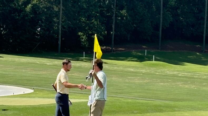 Garrett Engle (L) accepts congratulations from his opponent's caddie after tapping in on the 18th hole Engle, who plays at Tennessee-Chattanooga, won by shots at Druid Hills Golf Club, June 8, 2024.