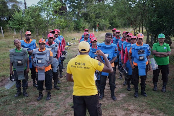 Thavarathnam Pushparani, second left in front row, listens to the safety instructions with her fellow workers before stepping into a contaminated mining area in Mankulam, Sri Lanka, Thursday, April 3, 2025. (AP Photo/Eranga Jayawardena)