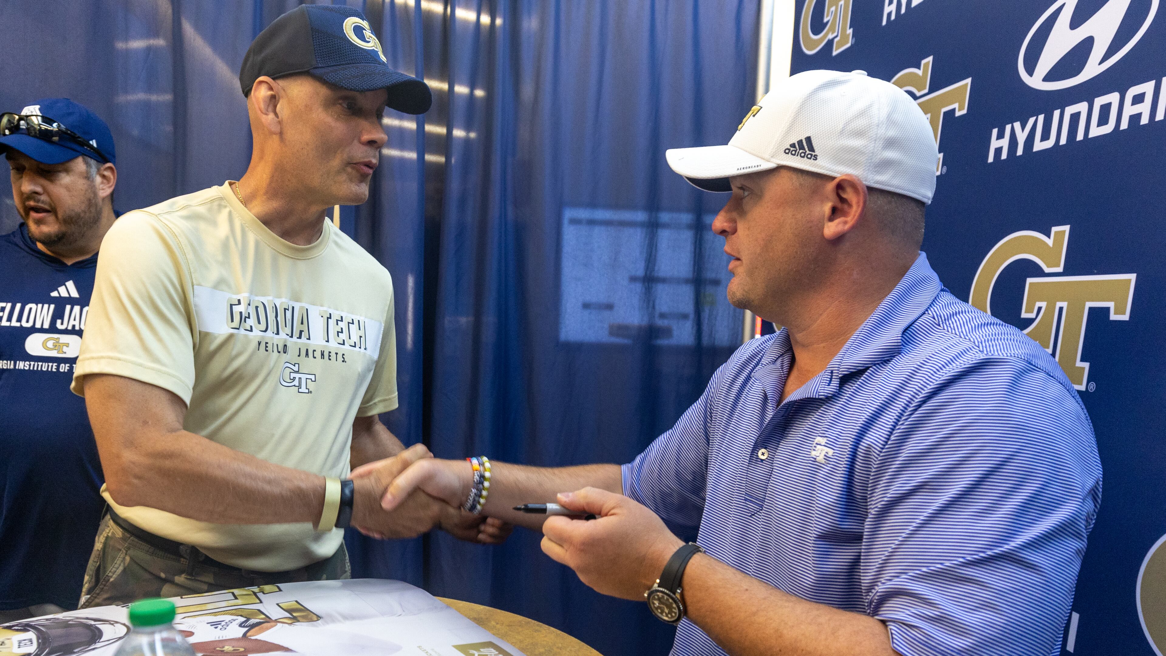 Georgia Tech coach Brent Key (right) shakes hands with Alan Womack after Key signed his poster during Georgia Tech football’s annual First Saturday on The Flats at Bobby Dodd Stadium on July 27, 2024. (Steve Schaefer / AJC)