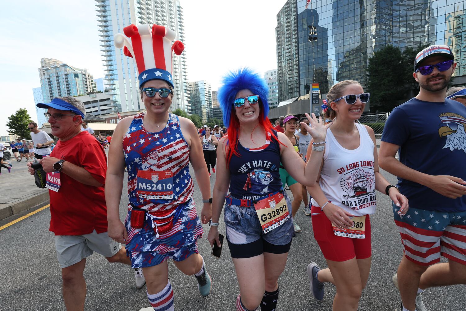 Costumed runners celebrate at the start of the 55th running of the Atlanta Journal-Constitution Peachtree Road Race in Atlanta on Thursday, July 4, 2024.   (Miguel Martinez / AJC)