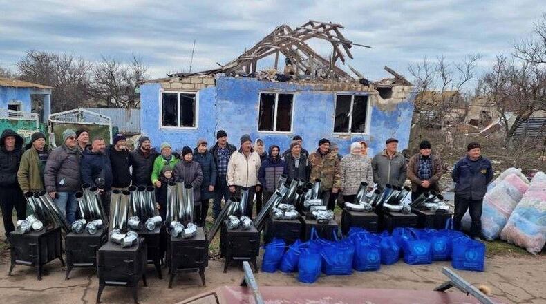 Ken Ward and volunteers stand in front of a damaged home in Ukraine, before handing out blankets and installing wood-fired stoves, which can be used for both heating and cooking. (Photo Courtesy of HelpingUkraine.U.S.)