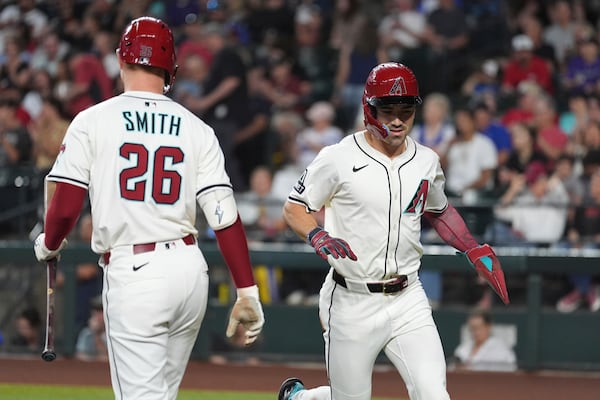 Arizona Diamondbacks' Corbin Carroll, right, celebrates his run scored against the Atlanta Braves with Diamondbacks' Pavin Smith (26) during the first inning of a baseball game Sunday, April 27, 2025, in Phoenix. (AP Photo/Ross D. Franklin)