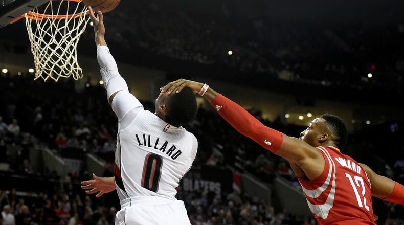 Portland Trail Blazers guard Damian Lillard (0) is fouled by Houston Rockets center Dwight Howard (12) as he drives to the basket during the second half of an NBA basketball game in Portland, Ore., Wednesday, Feb. 10, 2016. The Blazers won the game 116-103. (AP Photo/Steve Dykes)