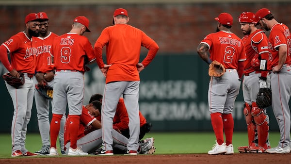Los Angeles Angels second baseman Christian Moore (4) is helped after being injured fielding a ball hit by Atlanta Braves' Ozzie Albies in the sixth inning of a baseball game, Wednesday, July 2, 2025, in Atlanta. (AP Photo/Mike Stewart)