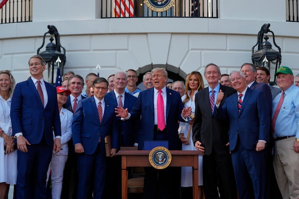President Donald Trump stands on stage after signing his signature bill of tax breaks and spending cuts at the White House, Friday, July 4, 2025, in Washington, surrounded by members of Congress and first lady Melania Trump. (AP Photo/Julia Demaree Nikhinson)
