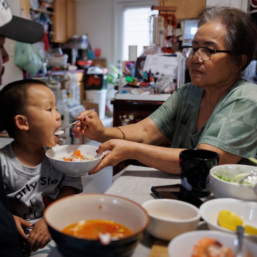 Lien Chang feeds her 2-year-old grandson Cairo Miu a bowl of rice next to his dad Jack Chang in her home on Monday, July 13, 2026, in San Francisco. (AP Photo/Juliana Yamada)