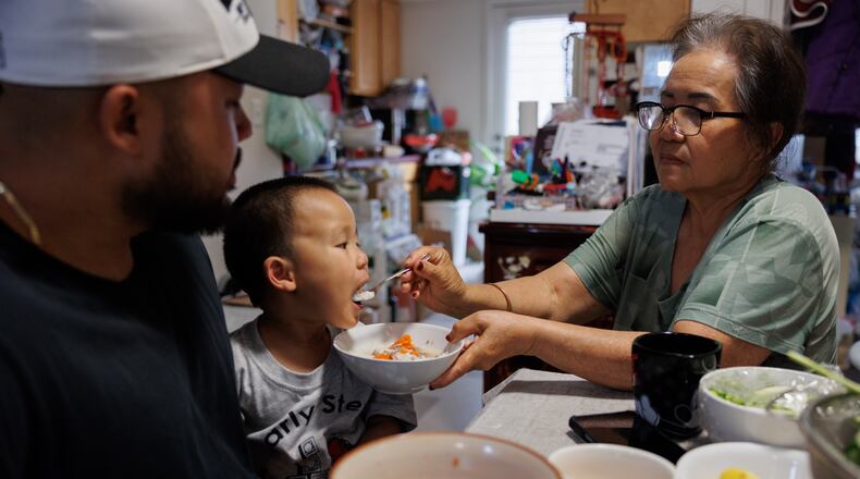 Lien Chang feeds her 2-year-old grandson Cairo Miu a bowl of rice next to his dad Jack Chang in her home on Monday, July 13, 2026, in San Francisco. (AP Photo/Juliana Yamada)