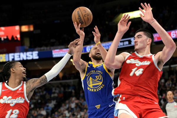 Golden State Warriors guard Stephen Curry (30) shoots between Memphis Grizzlies guard Ja Morant (12) and center Zach Edey (14) in the first half of an NBA basketball game Tuesday, April 1, 2025, in Memphis, Tenn. (AP Photo/Brandon Dill)