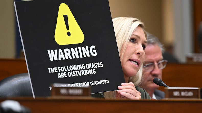 U.S. Rep. Marjorie Taylor Greene (R-Rome) holds up a warning sign during a House Committee on Oversight and Accountability hearing over the tax case against the president's son, Hunter Biden, on Capitol Hill in Washington, July 19, 2023. (Kenny Holston/The New York Times)