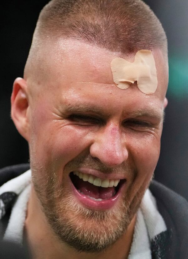 With his head bandaged after an injury, Boston Celtics center Kristaps Porzingis (8) laughs after defeating the Orlando Magic in game 2 of a first-round NBA playoff basketball series, Wednesday, April 23, 2025, in Boston. (AP Photo/Charles Krupa)