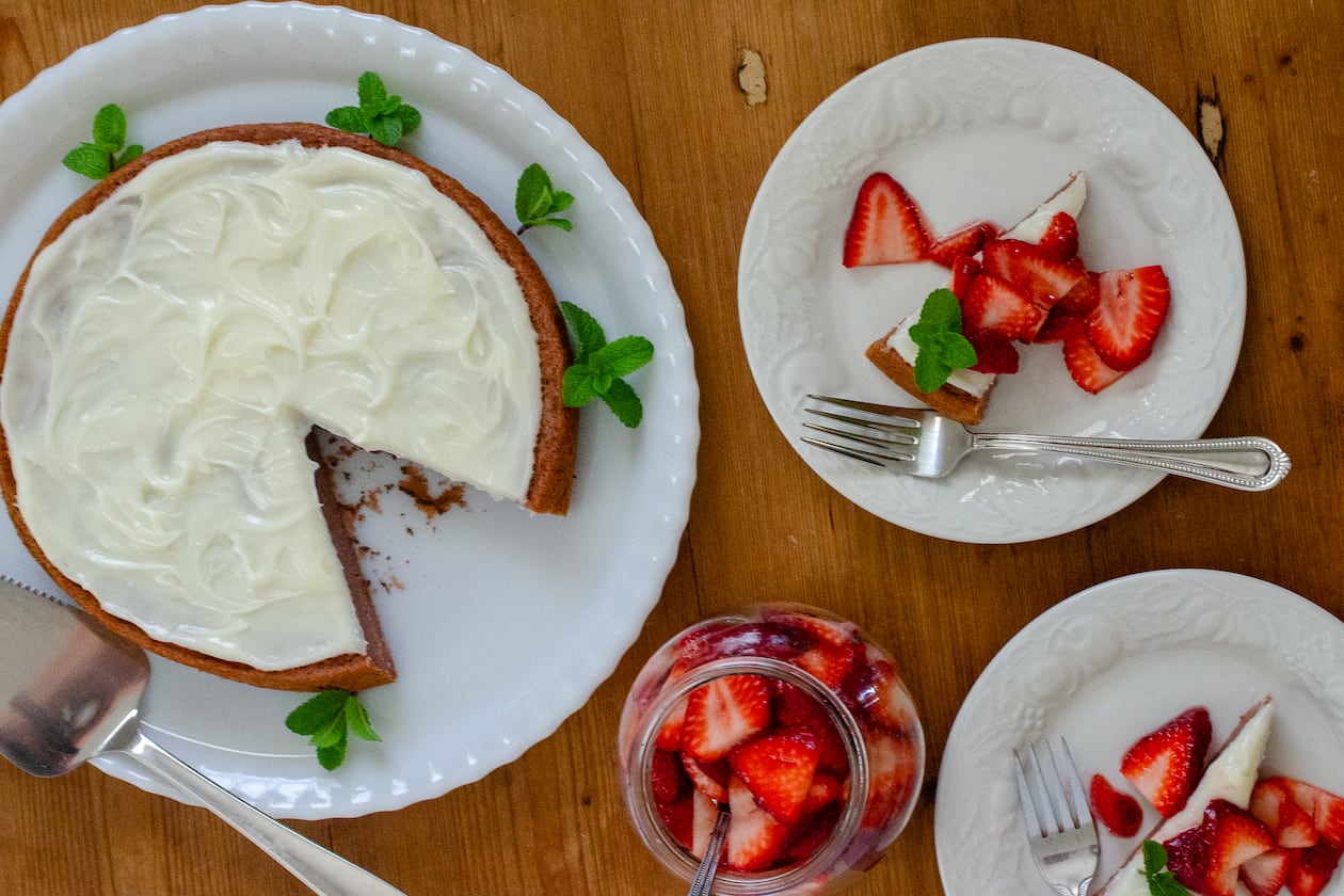 This one-layer strawberry cake is topped with a Neufchatel frosting and served with jam-kissed fresh strawberries. (Virginia Willis for The Atlanta Journal-Constitution)