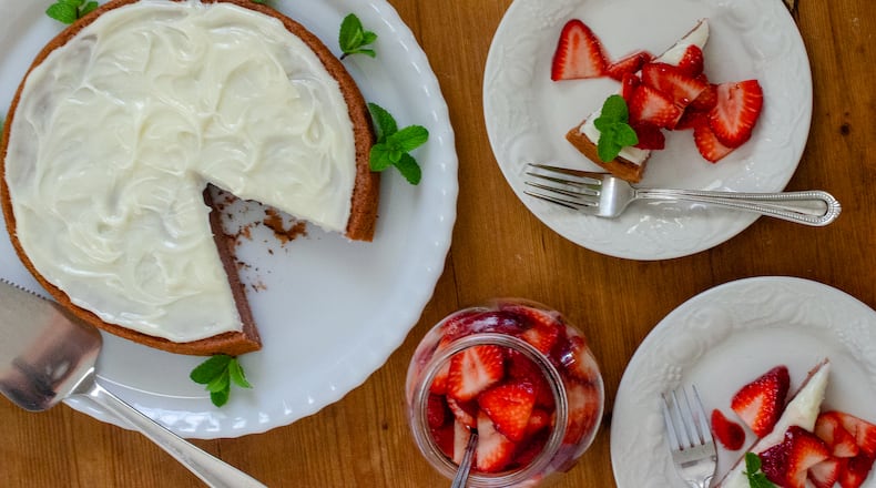 This one-layer strawberry cake is topped with a Neufchatel frosting and served with jam-kissed fresh strawberries. (Virginia Willis for The Atlanta Journal-Constitution)