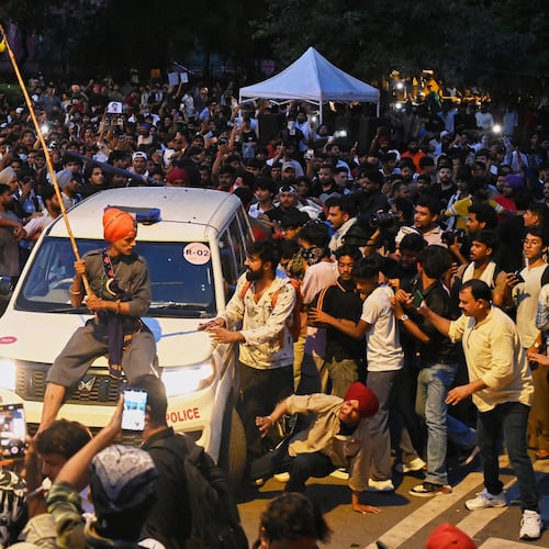 A protestor sits on the hood of a police car during a demonstration demanding educational reforms as part of the Cockroach Janta Party's ongoing protest movement in New Delhi, India, Wednesday, July 22, 2026. (AP Photo/Vipin)