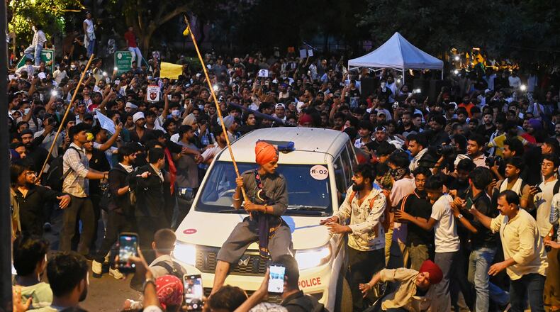 A protestor sits on the hood of a police car during a demonstration demanding educational reforms as part of the Cockroach Janta Party's ongoing protest movement in New Delhi, India, Wednesday, July 22, 2026. (AP Photo/Vipin)