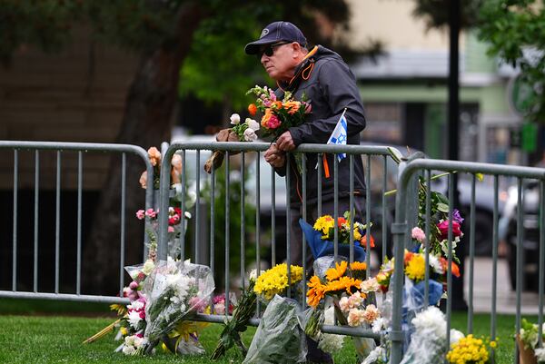 A man affixes a bouquet of flowers to a makeshift memorial for victims of an attack outside of the Boulder County, Colo., courthouse Tuesday, June 3, 2025, in Boulder, Colo. (AP Photo/David Zalubowski)
