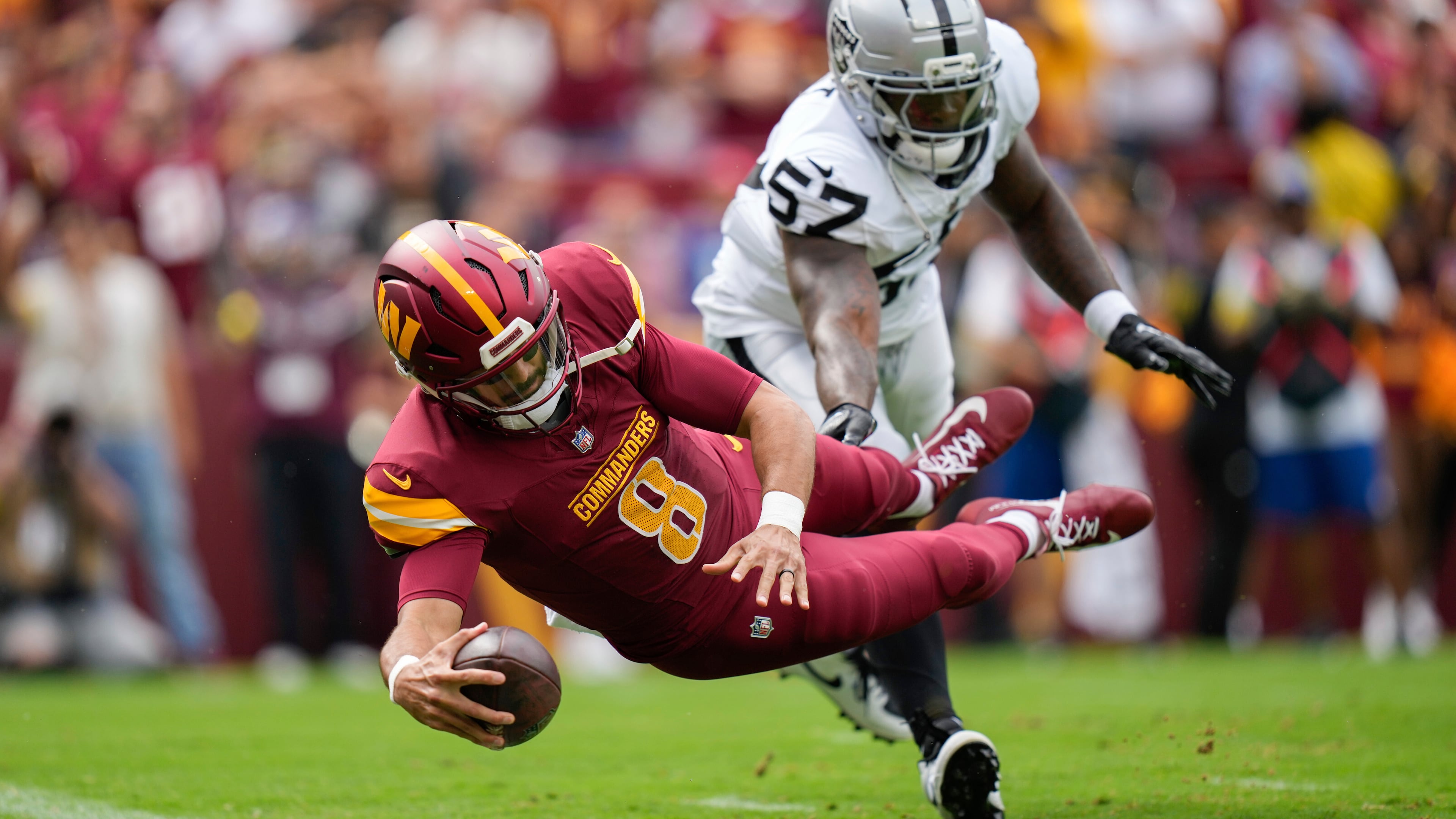 Washington Commanders quarterback Marcus Mariota scores a touchdown as Las Vegas Raiders linebacker Germaine Pratt defends during an NFL football game Sunday, Sept. 21, 2025, in Landover, Md. (Stephanie Scarbrough/AP)