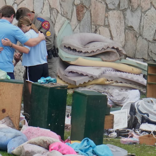 FILE - An officer prays with a family as they pick up items at Camp Mystic in Hunt, Texas on July 9, 2025. (AP Photo/Ashley Landis, file)