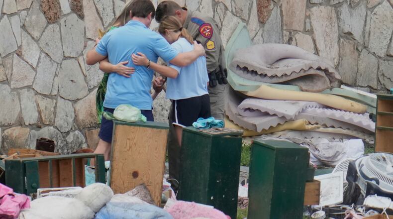 FILE - An officer prays with a family as they pick up items at Camp Mystic in Hunt, Texas on July 9, 2025. (AP Photo/Ashley Landis, file)