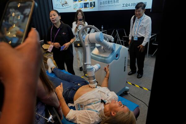 A visitor tests the AUBO therapy robot at the the 137th Canton Fair in Guangzhou in southern China's Guangdong province on Wednesday, April 16, 2025. (AP Photo/Ng Han Guan)